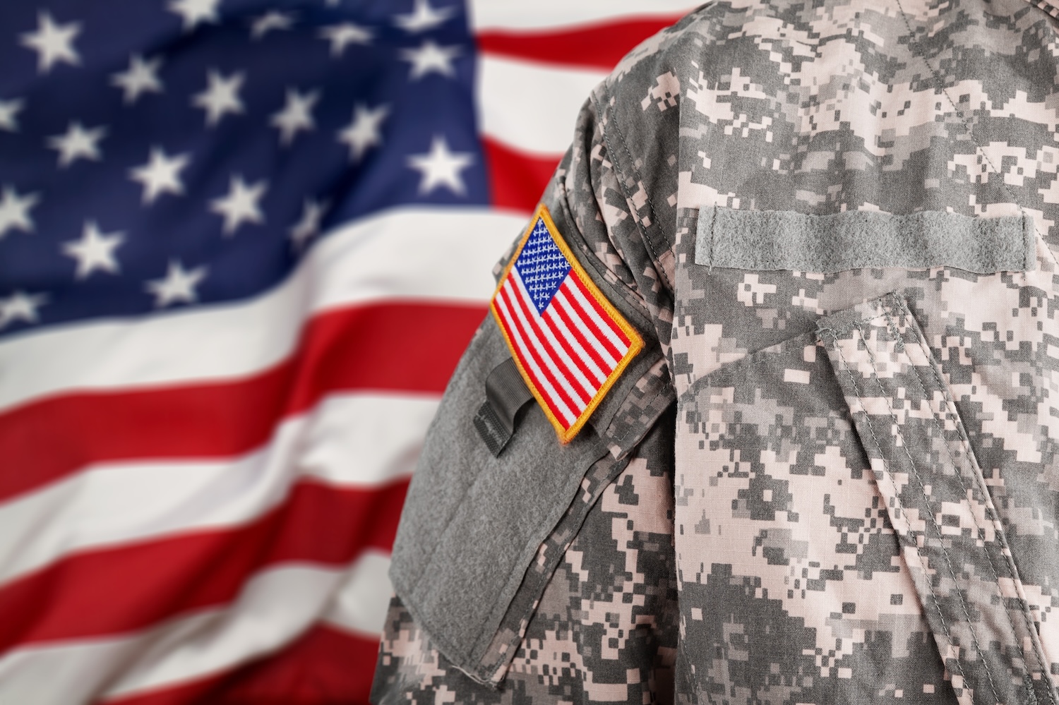 Back of a veteran in uniform with a flag in front of them